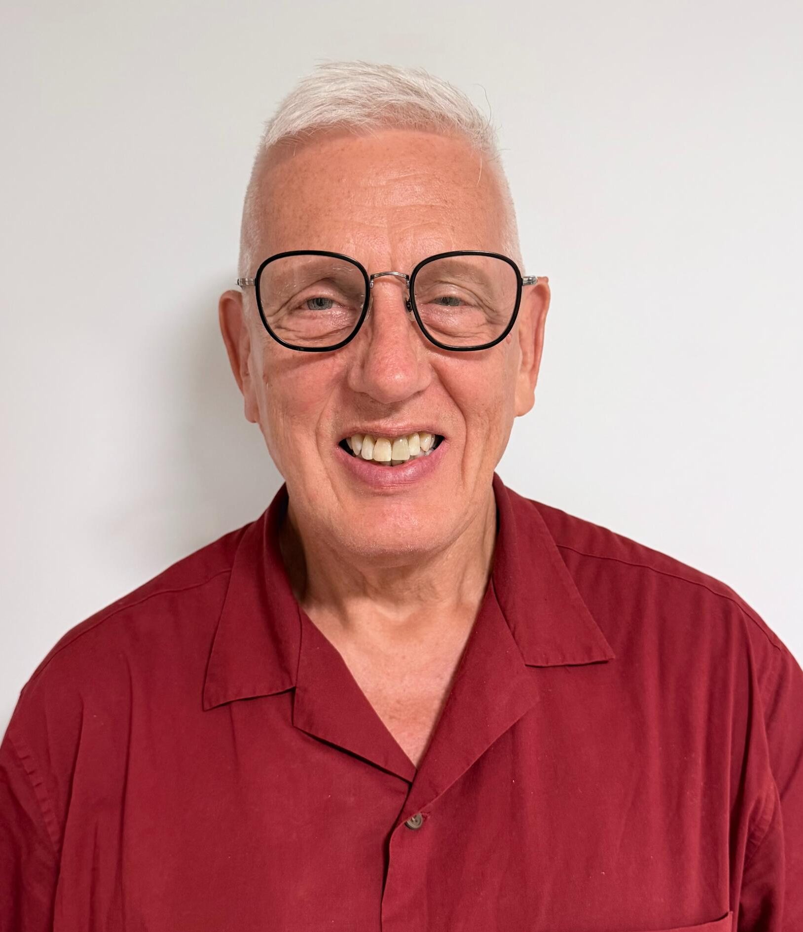 man with white hair in glasses and a red shirt