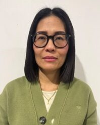 woman with dark hair in thick-framed glasses and green cardigan
