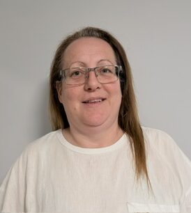 woman with brown hair smiling in a white t-shirt